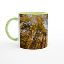 Ceramic mug with sunlit autumn forest artwork and green handle