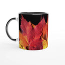 Ceramic mug with black interior and vivid red and yellow autumn leaves artwork