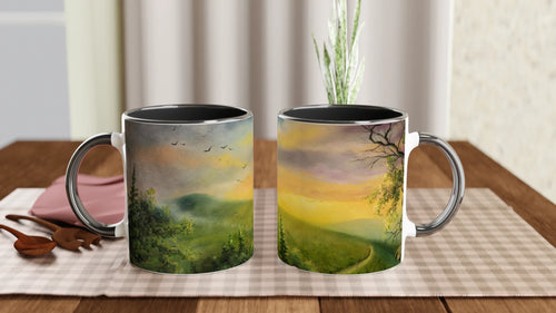 Two ceramic mugs with forest sunset artwork on a dining table