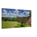 Side angle of panoramic canvas art featuring a bright spring landscape with a singular tree, hills, and fluffy clouds