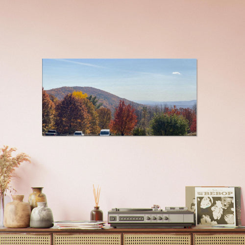 Canvas print of colorful autumn trees and mountains displayed above a shelf in a warm living space