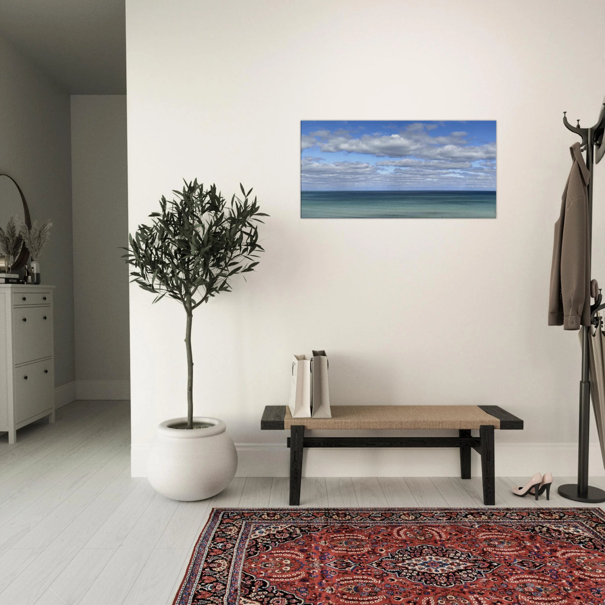 Ocean and sky canvas art in an elegant entryway with potted plant and red rug
