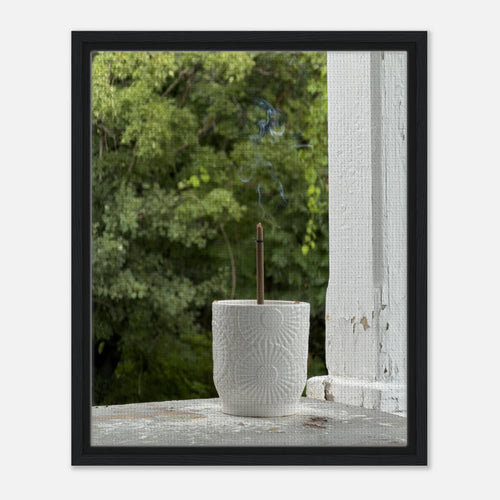 Black wood framed canvas of incense on porch against leafy trees